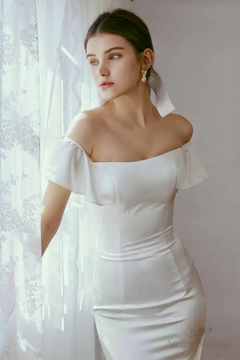 Vue de face d'une robe de mariée col bateau mettant en valeur les épaules dénudées.