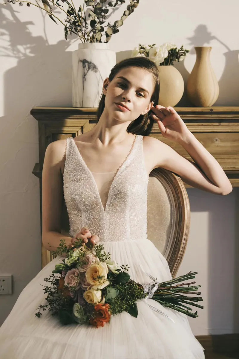 Robe de mariée bohème sur-mesure avec dentelle et fleurs 3D, tenue par une mariée avec bouquet champêtre