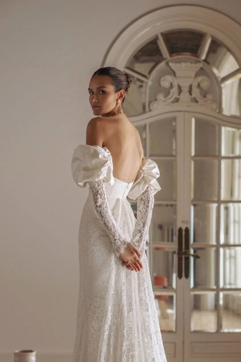 Vue de dos d'une mariée portant des manches amovibles fluides qui complètent une robe bustier.