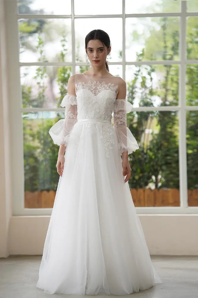 Mariée portant une paire de manches amovibles en tulle et dentelle, transformant une robe bustier simple en une tenue de mariage romantique et féerique.