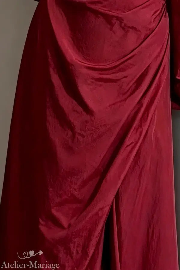 Vue sur le bas de la robe fendue en taffetas montrant la brillance unique du tissu rouge bordeaux.