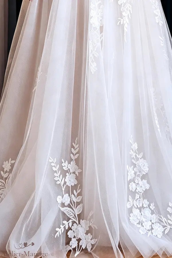 Détails des broderies romantiques au bas d'une robe de mariée fluide et bohème.
