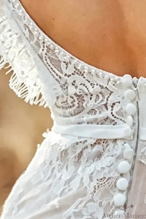 Détail des boutons recouverts à la main sur le dos d'une robe de mariée en dentelle.