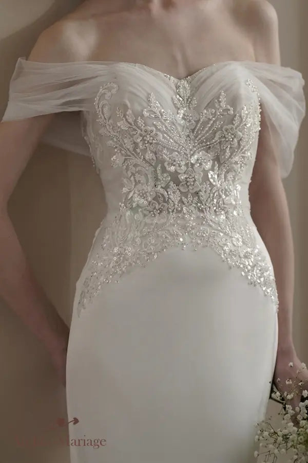 Détails luxueux de broderies perlées soulignant la taille et le buste d'une robe de mariée couture.