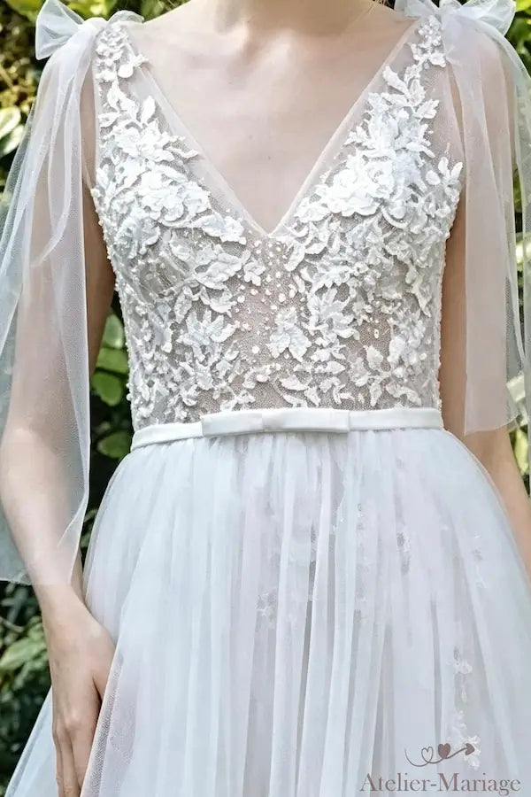 Zoom sur le bustier en dentelle florale et sa ceinture fine avec petit nœud plat.