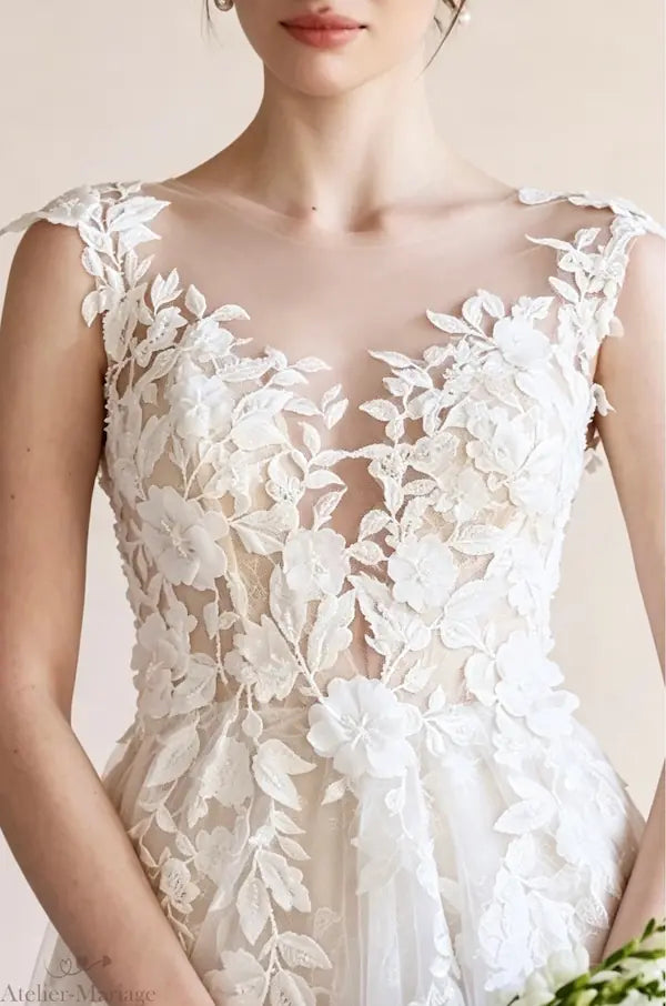 Zoom sur le bustier fleuri et le travail de perlage délicat sur tulle illusion d'une robe de mariée sur-mesure.
