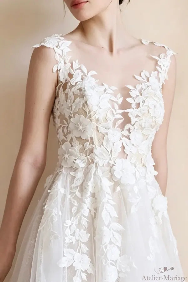 Cascade de broderies florales blanches et finitions haute couture sur une jupe de mariée fluide.
