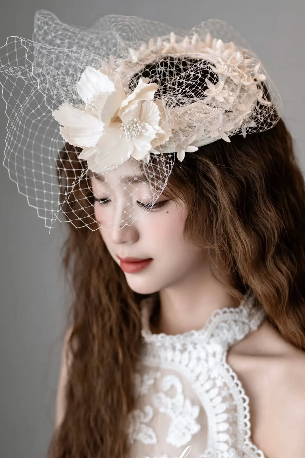 Modèle portant le chapeau voilette Aura avec des cheveux lâchés ondulés (style wavy) pour un mariage chic.
