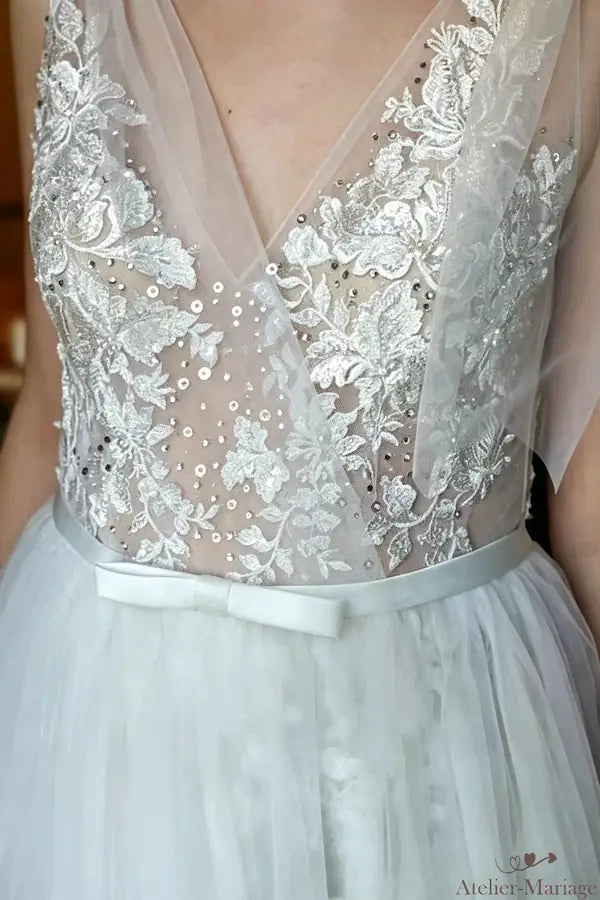 Décolleté plongeant en V avec dentelle scintillante et paillettes discrètes.