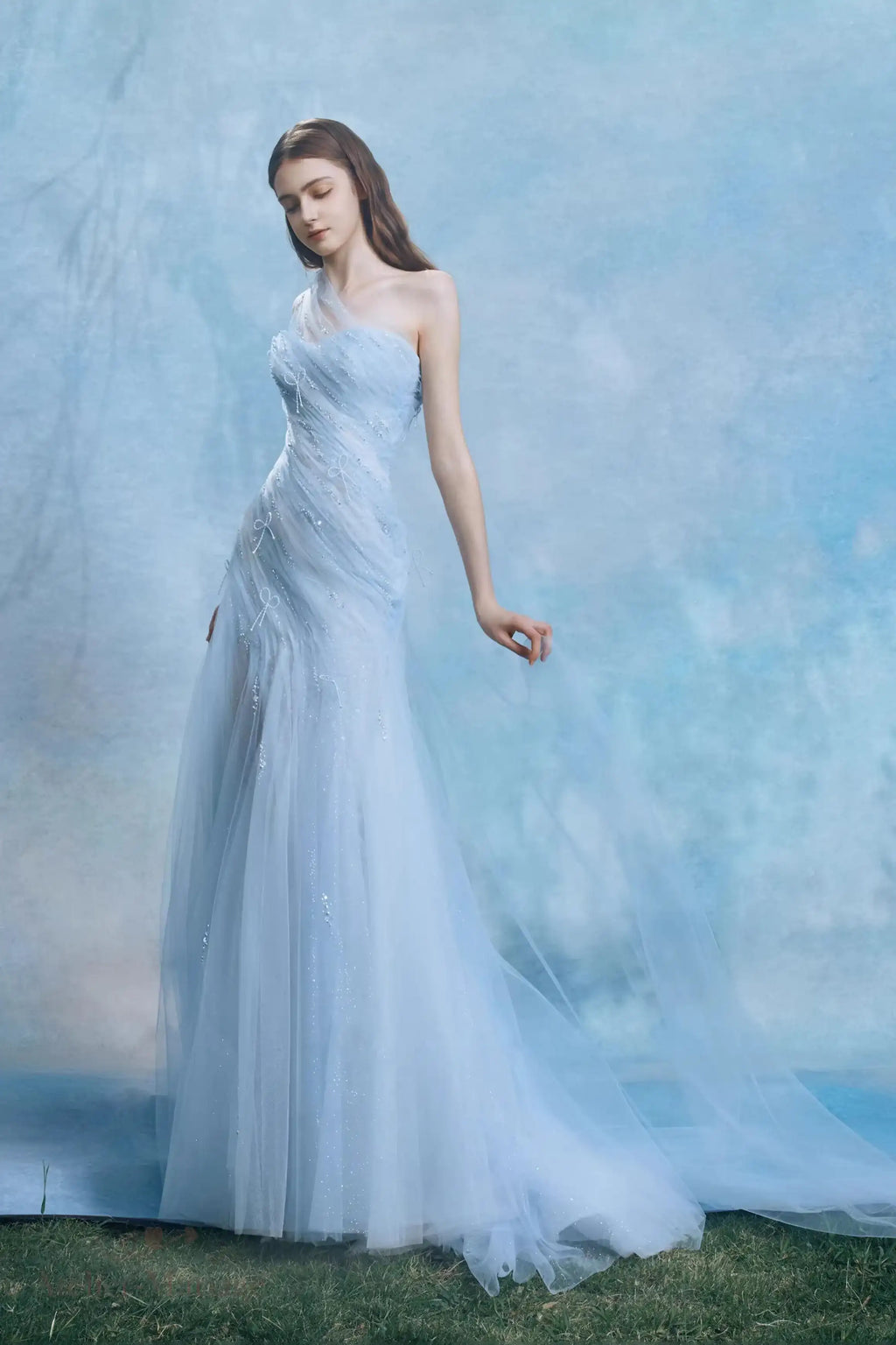 Vue sur le corsage drapé asymétrique orné de petits nœuds délicats sur la robe bleue.