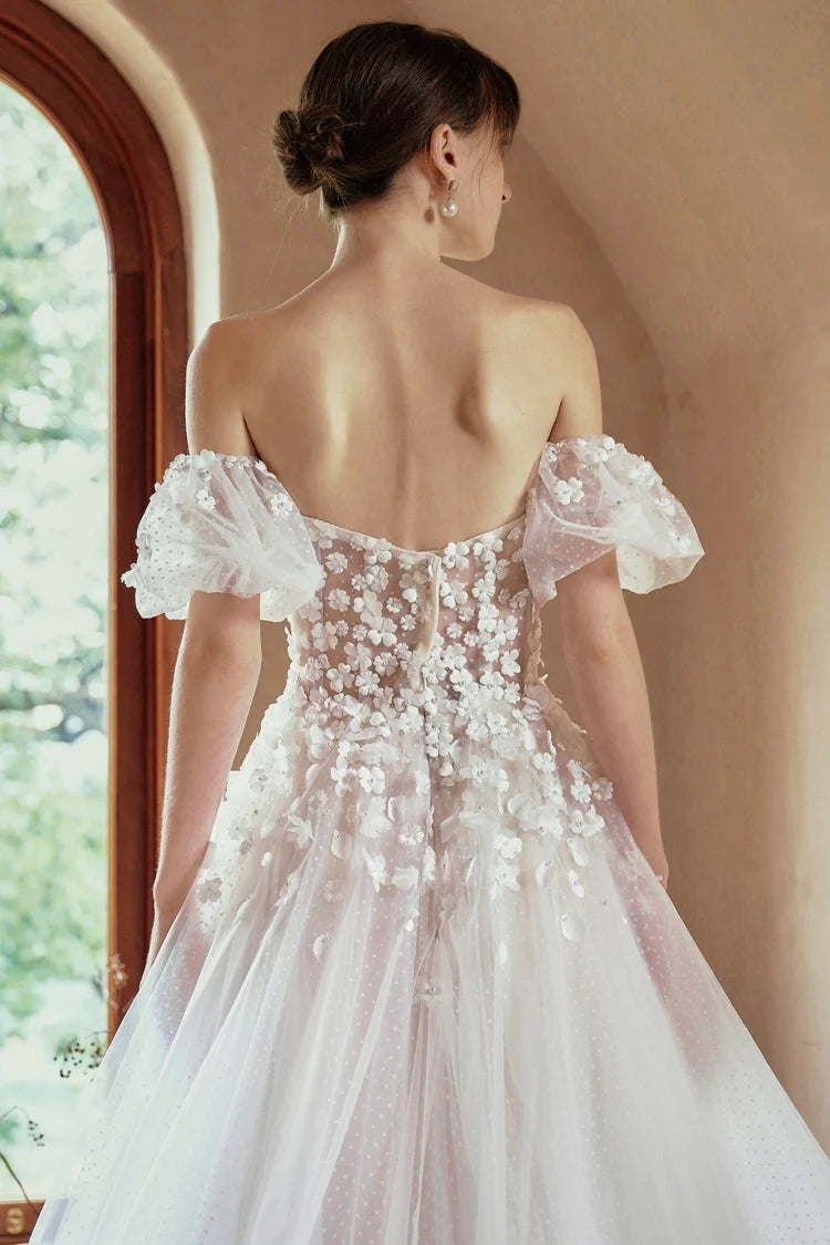 Détail du dos avec corset et fleurs 3D brodées sur tulle transparent.