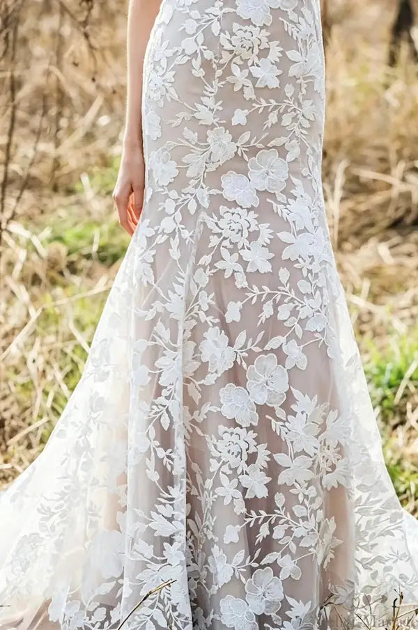 Vue du bas d'une robe de mariée sirène montrant la coupe ajustée et les finitions précises de l'ourlet en dentelle.