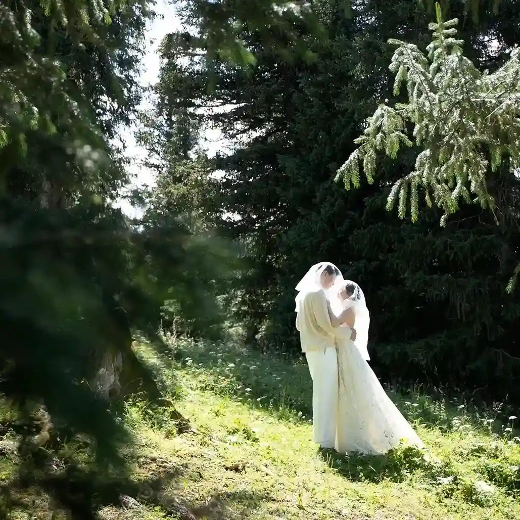 Couple de mariés rayonnants marchant main dans la main en pleine nature, la mariée porte une robe fluide et vaporeuse ultra-légère