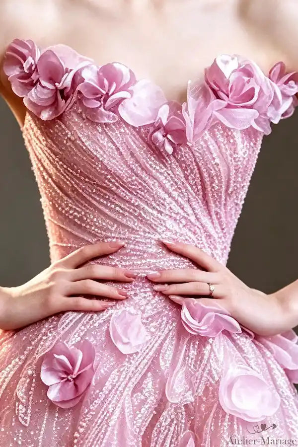 Détail des fleurs 3D artisanales et perles sur le décolleté d'une robe princesse rose.