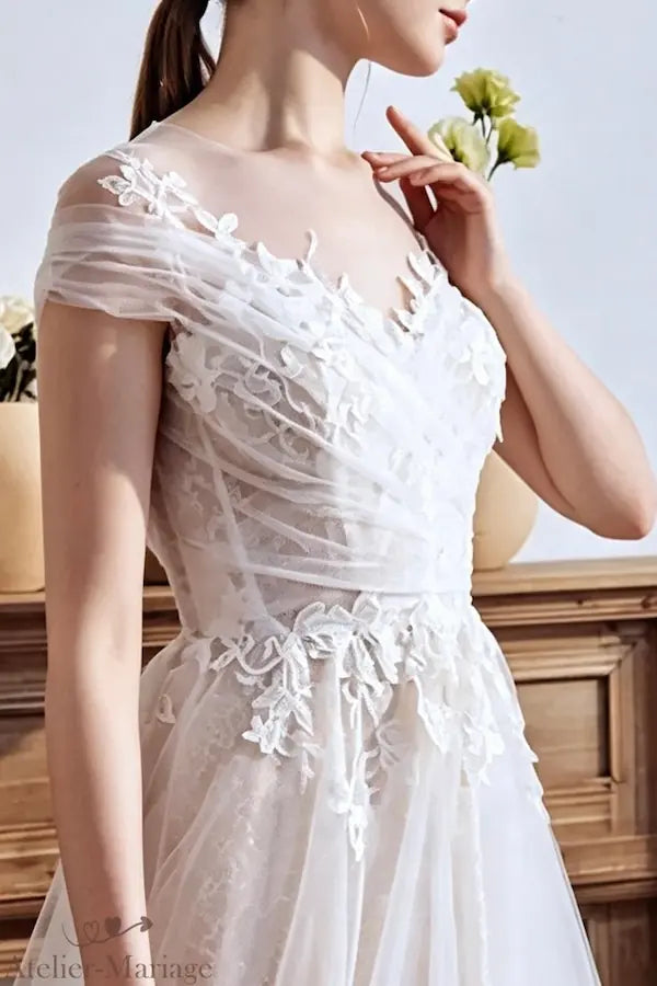 Zoom sur le décolleté en V bordé de perles et broderies florales artisanales.