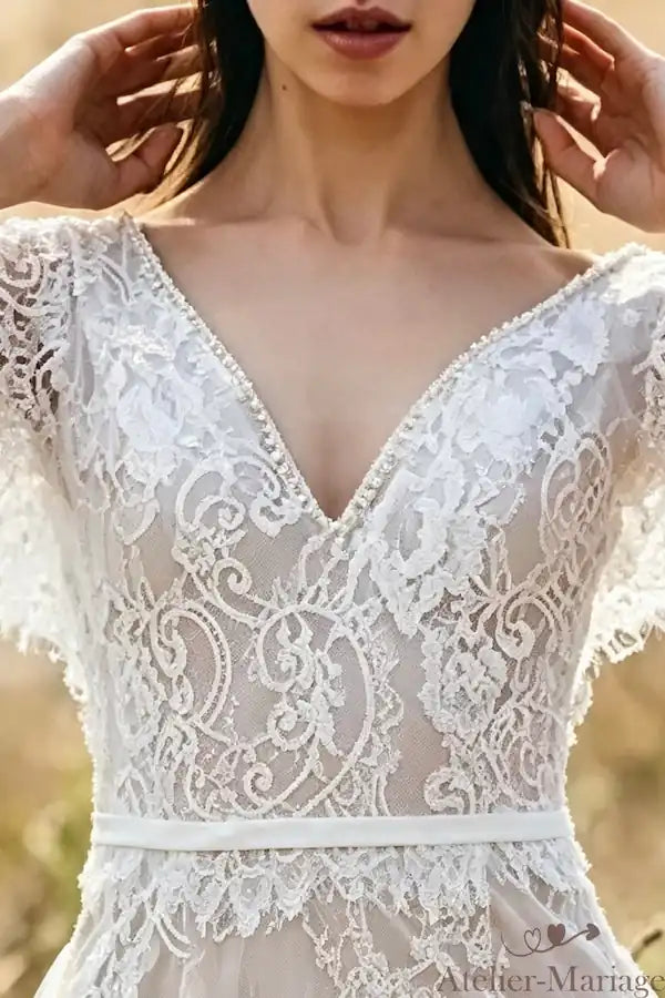 Détails de la dentelle florale sur le décolleté en V d'une robe de mariée sirène.