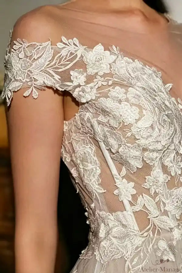 Détails de la dentelle florale sur l'épaule d'une robe de mariée col bateau, artisanat traditionnel.
