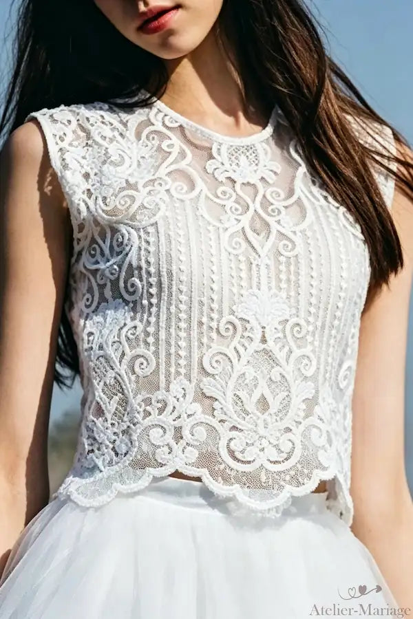 Gros plan sur la dentelle florale artisanale du top de mariée bohème, un travail de broderie précis et délicat sur tulle.