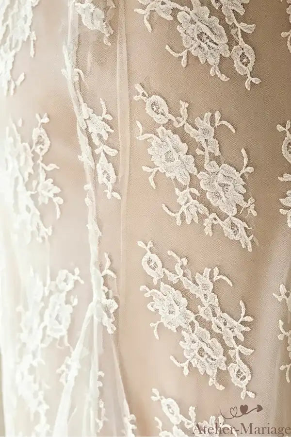 Zoom sur les motifs de dentelle florale placés et cousus manuellement sur le tulle.
