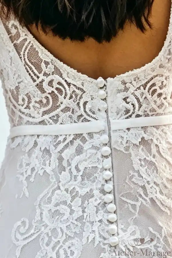 Gros plan sur le motif floral de la dentelle s'épanouissant sur le dos de la mariée.
