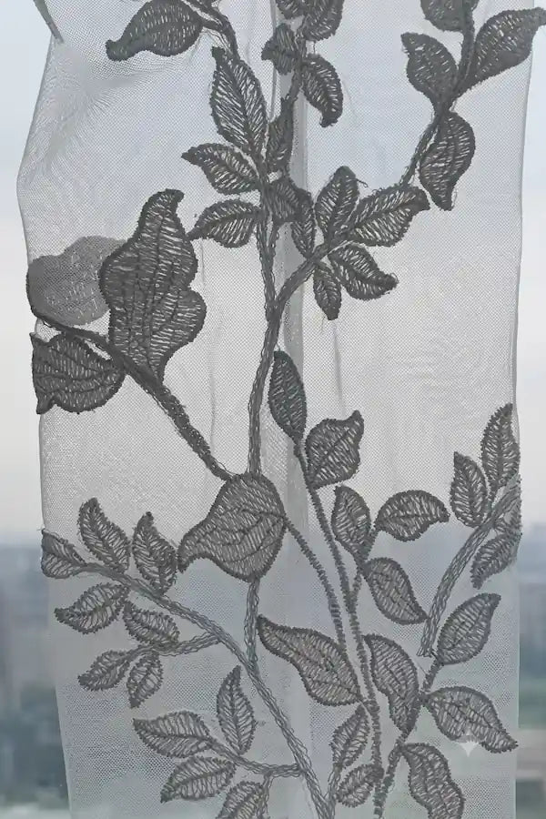 Détails des broderies florales blanches en relief sur tulle transparent haut de gamme.