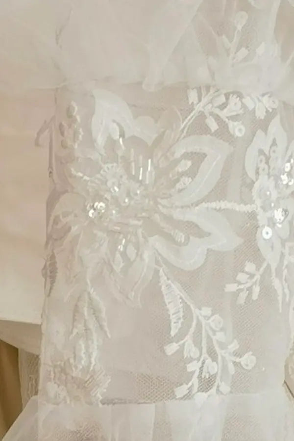 Détail de la broderie florale et des paillettes irisées sur la manche amovible en dentelle — finition haute couture