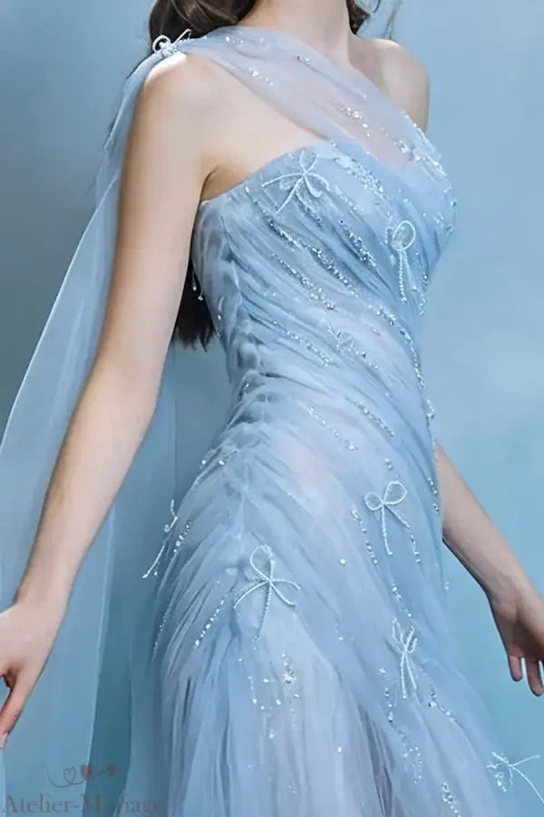 Détail du bustier drapé en tulle bleu brume orné de nœuds perlés scintillants faits main, focus sur le travail artisanal.