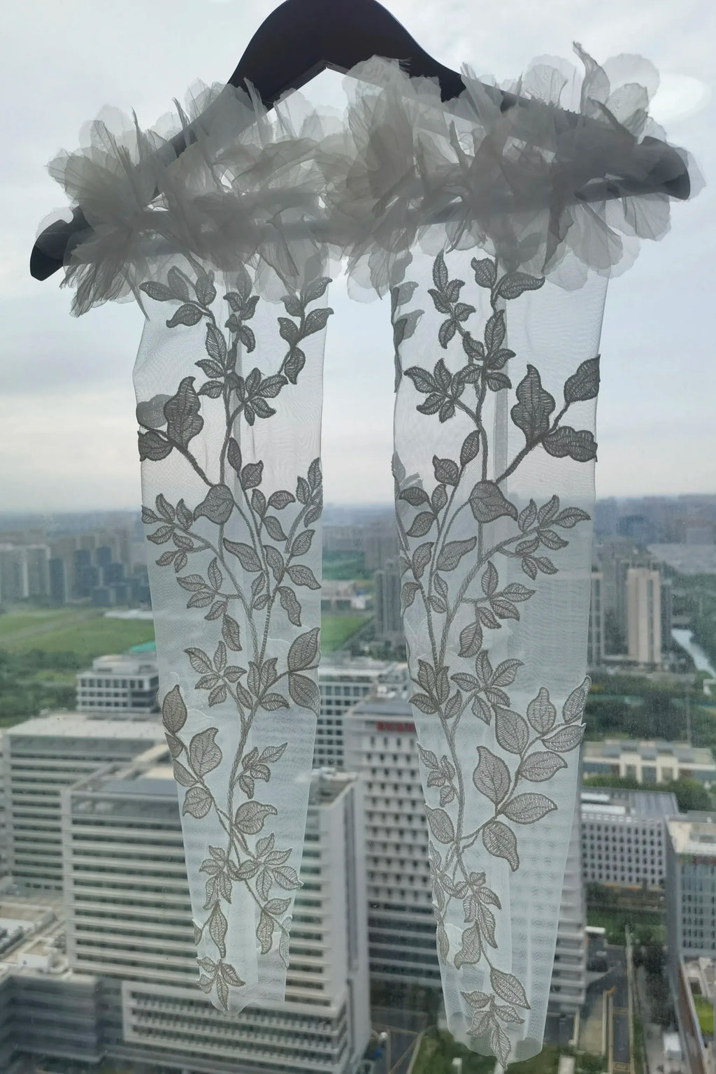 Gros plan sur le motif végétal symétrique et les feuilles brodées sur tulle transparent.