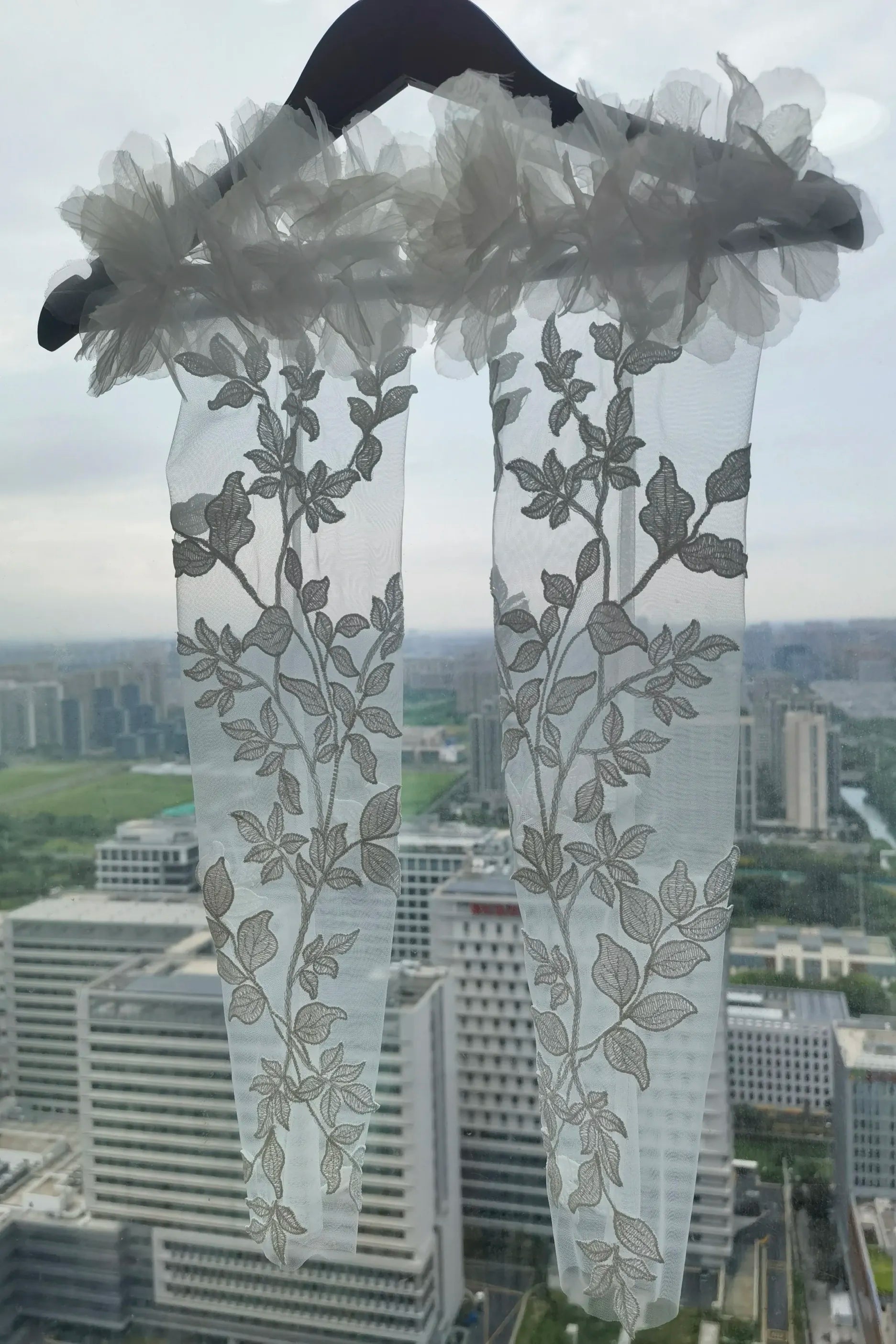 Gros plan sur le motif végétal symétrique et les feuilles brodées sur tulle transparent.