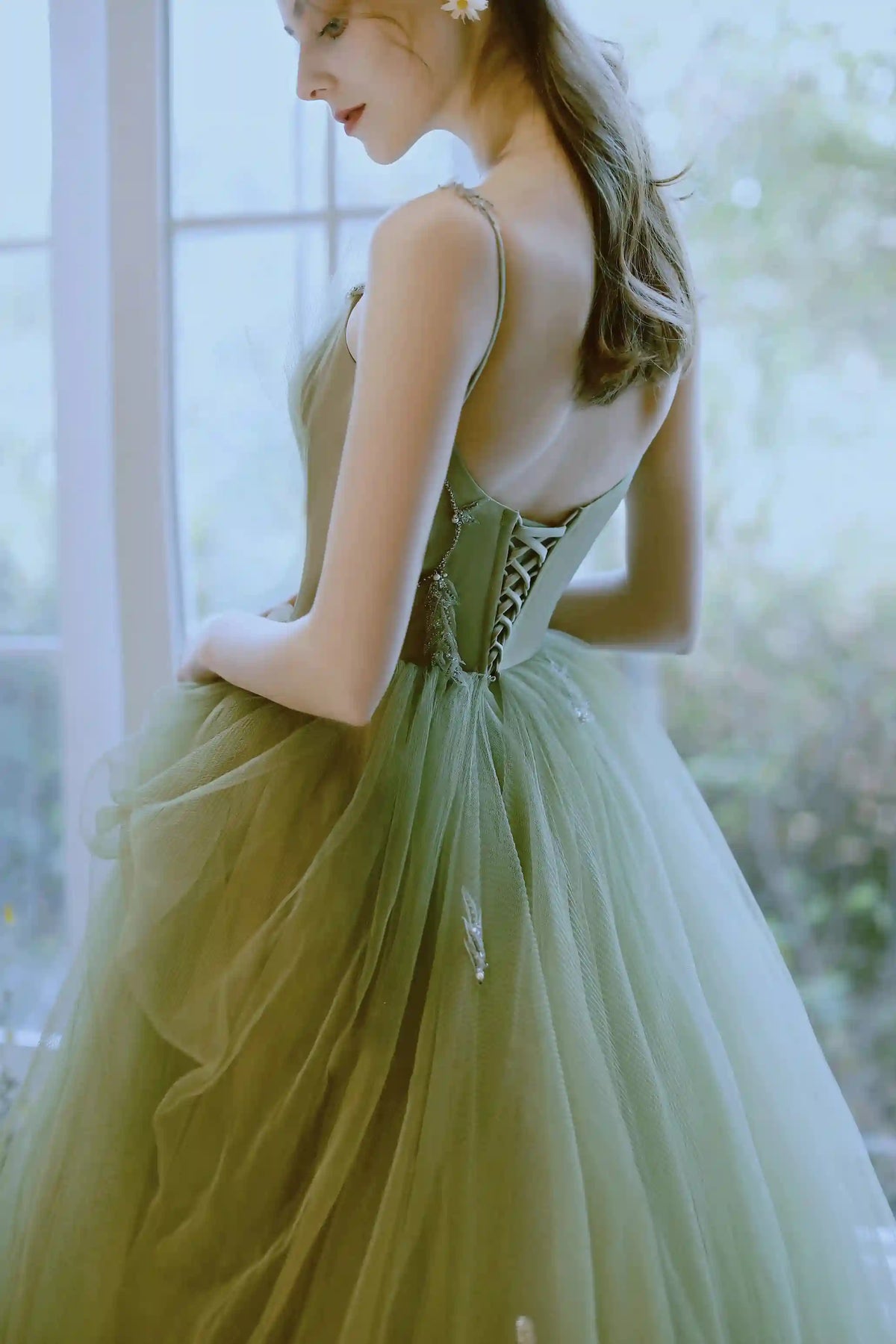Gros plan sur le dos nu de la robe de mariée verte montrant la fermeture corset à laçage.