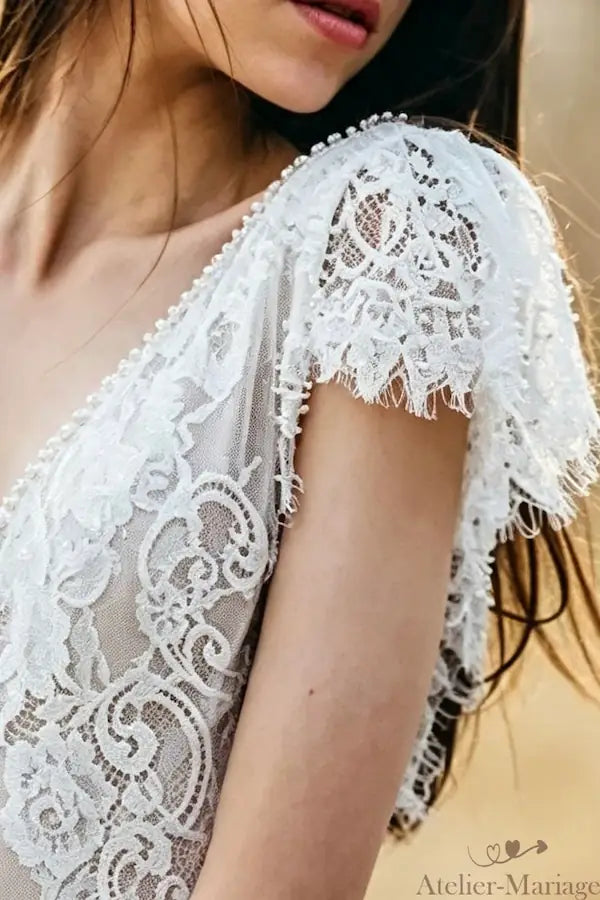 Bordure de dentelle travaillée à la main sur l'épaule d'une robe sur-mesure.