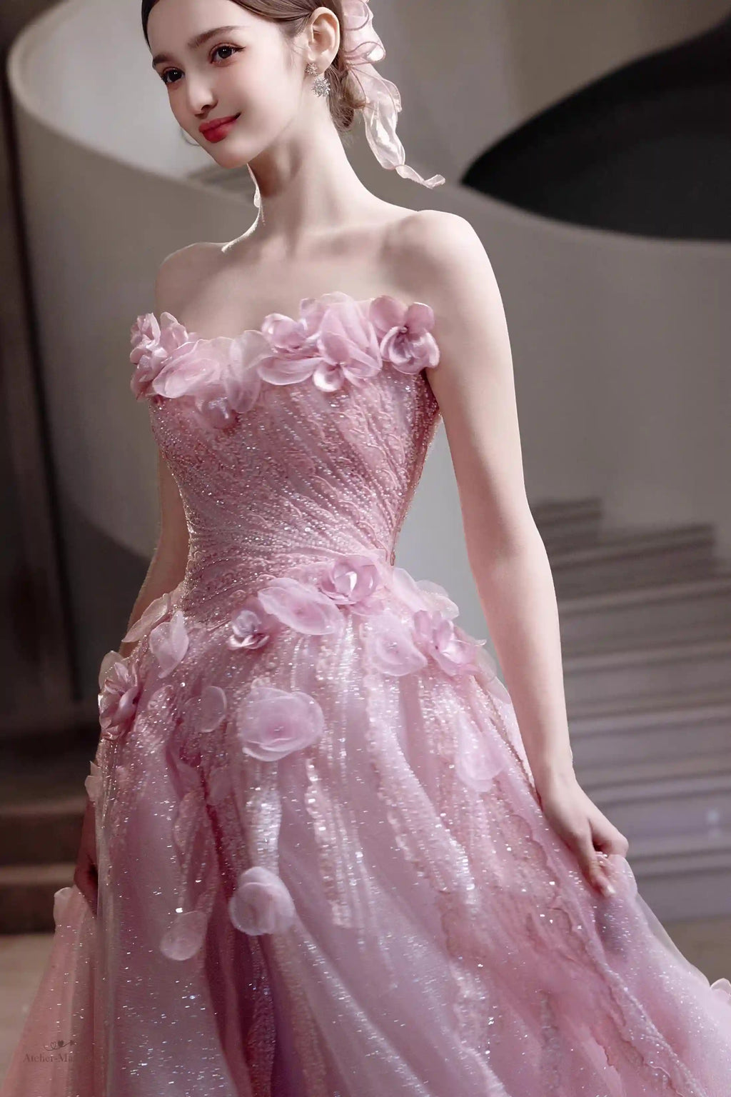 Détail haute couture des fleurs en relief et du tulle rose poudré brillant de la robe.