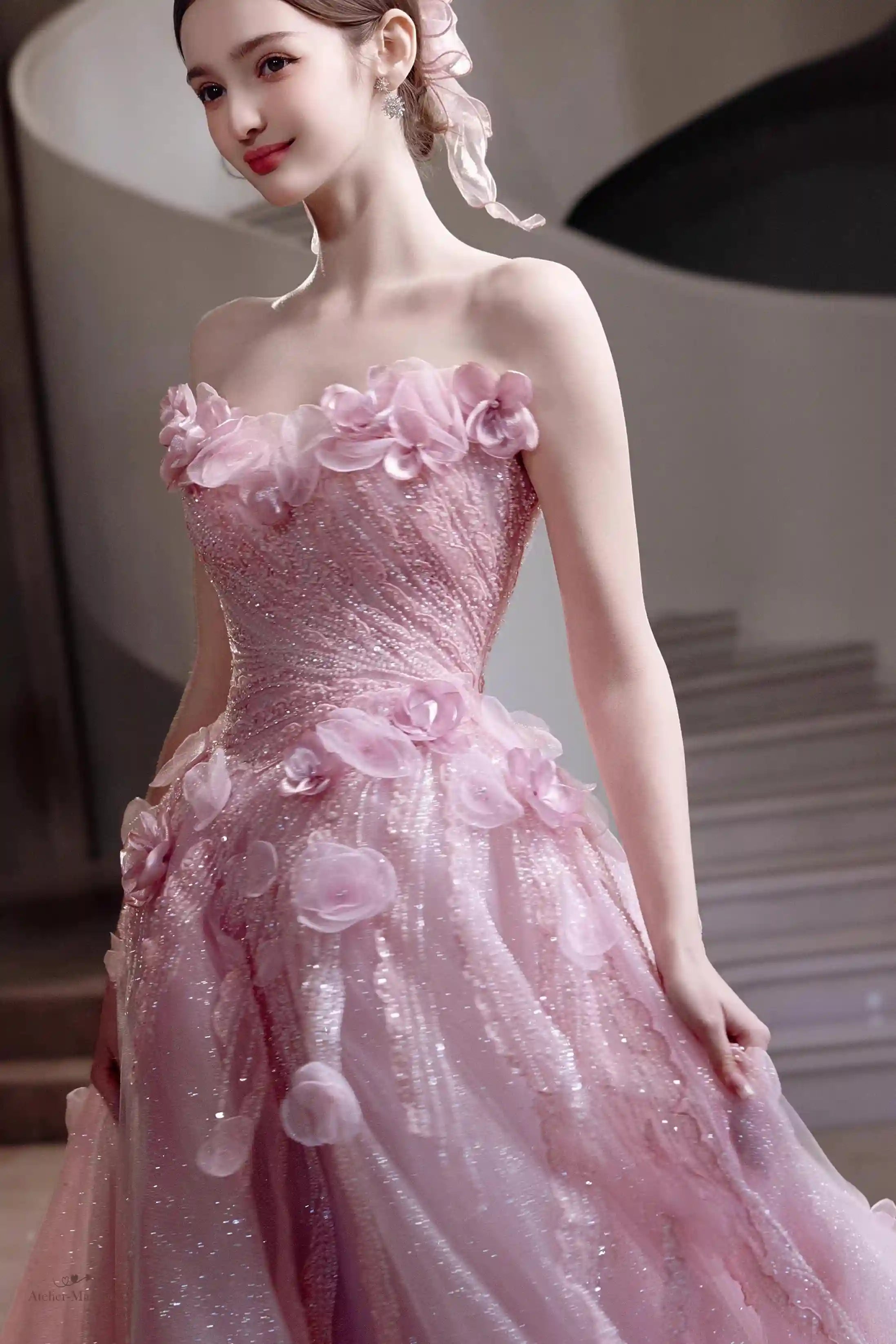 Détail haute couture des fleurs en relief et du tulle rose poudré brillant de la robe.