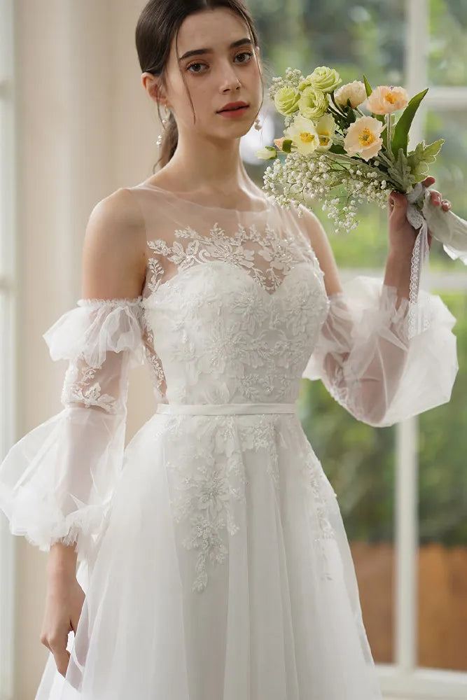 Gros plan sur les détails de broderie : dentelle perlée et sequins discrets sur une manche amovible, avec finition poignet élastiqué et volanté.