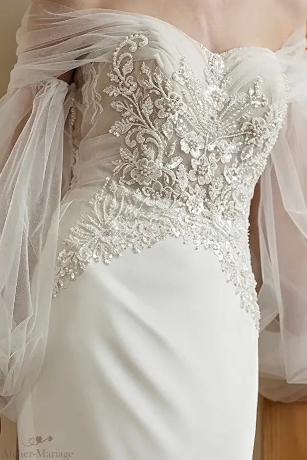 Gros plan sur le travail minutieux de perlage artisanal et de broderie sur le bustier de la robe.