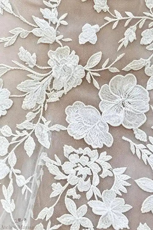 Gros plan sur la broderie de dentelle raffinée d'une robe de mariée bohème sirène, illustrant le travail méticuleux de l'atelier.