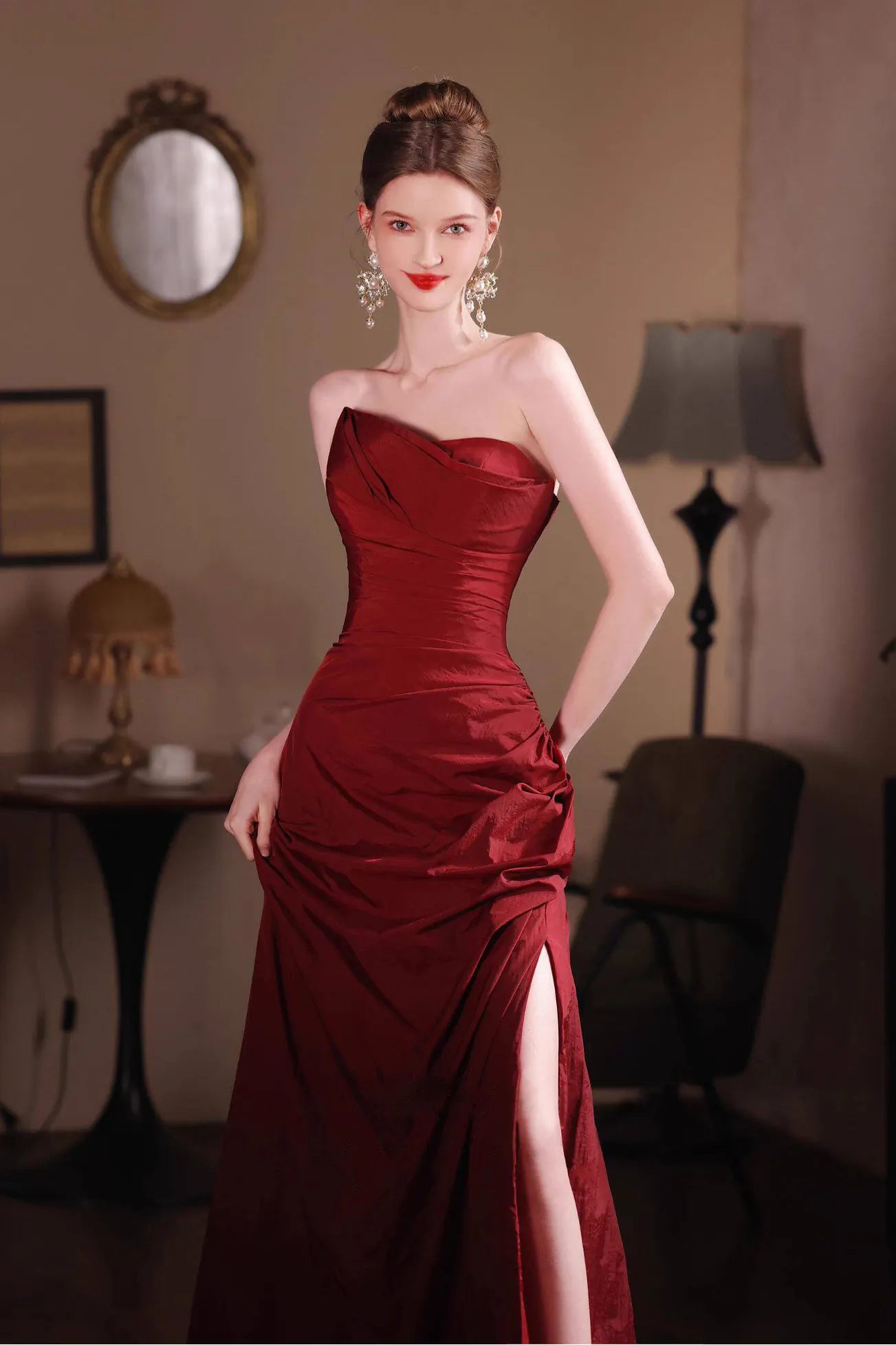 Détail du tissu en taffetas à l'aspect froissé naturel et du drapé haute couture sur la robe rouge bordeaux.