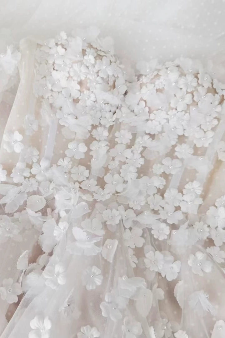Gros plan sur le travail artisanal des fleurs 3D et perles sur le tulle.