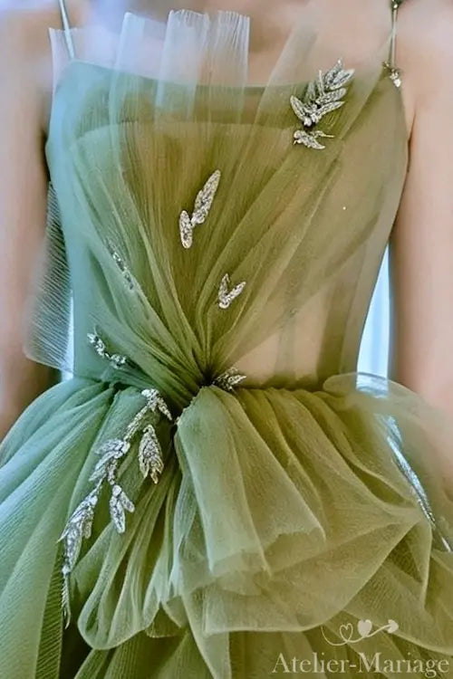 Zoom sur les détails plissés main en tulle vert sauge avec ornements scintillants, Atelier-Mariage.fr.