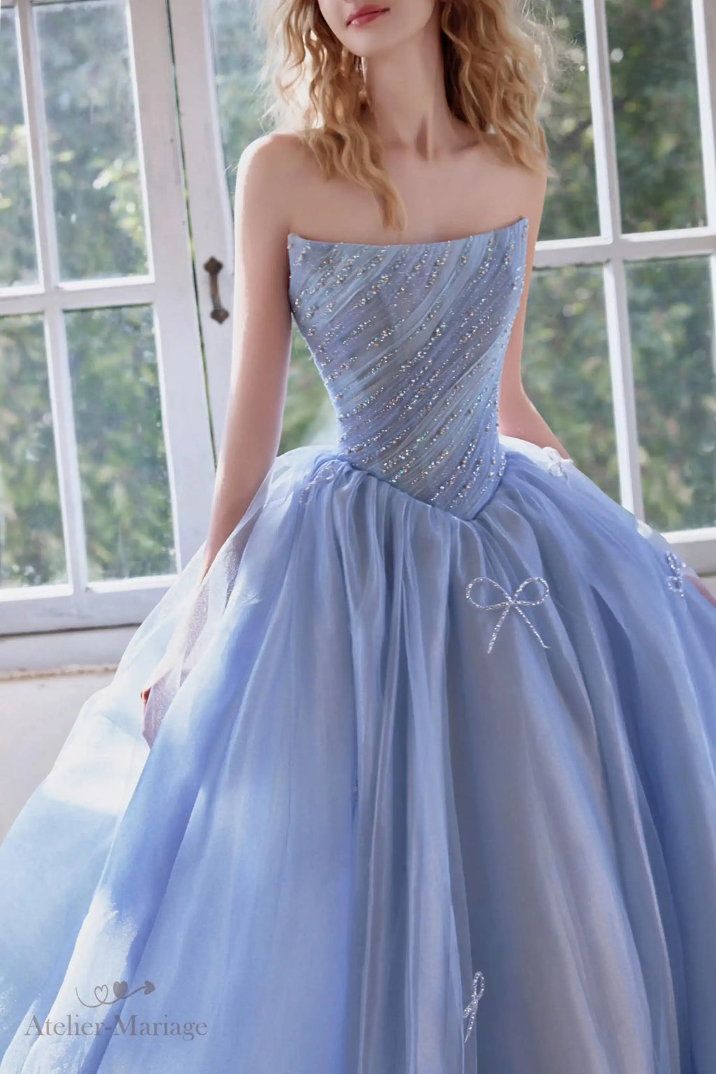 Détail haute couture du bustier scintillant avec des lignes de strass et de délicats nœuds en tulle bleu.