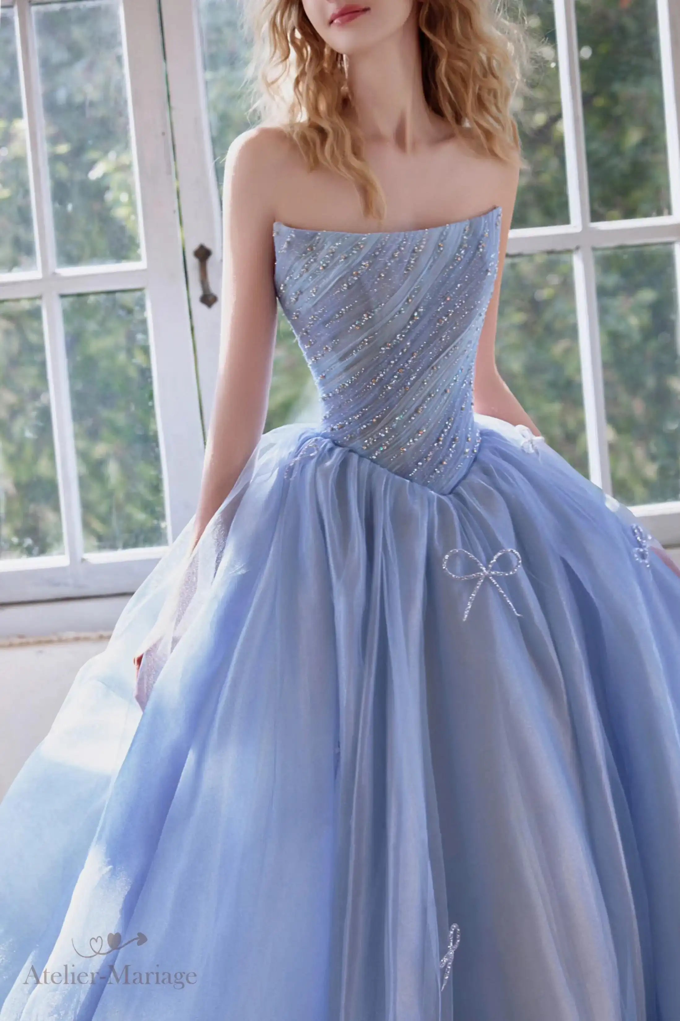 Détail haute couture du bustier scintillant avec des lignes de strass et de délicats nœuds en tulle bleu.