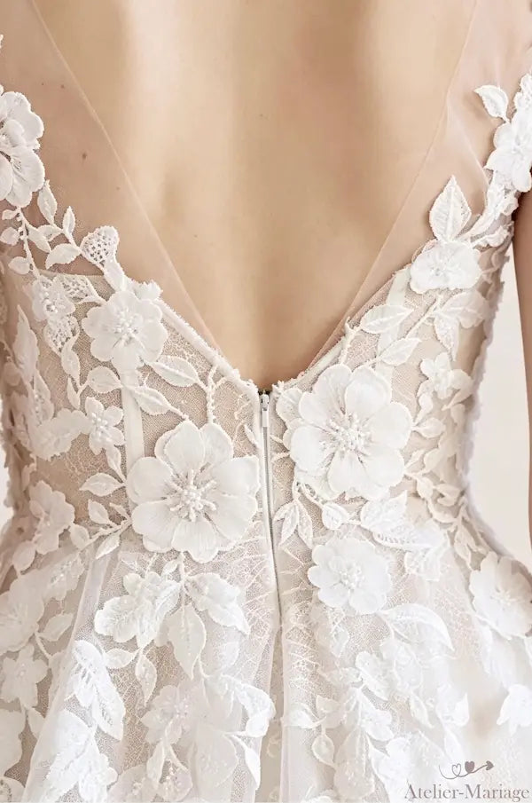 Détail du dos nu en V avec applications de fleurs 3D artisanales sur une robe de mariée bohème chic premium.