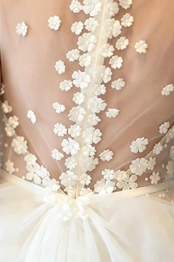 Vue rapprochée du dos nu plongeant orné de motifs floraux en relief sur tulle invisible effet seconde peau.