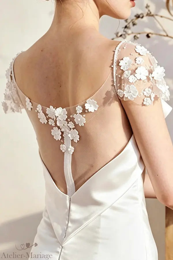 Vue du dos nu en V d'une robe de mariée sirène en satin, soulignant les motifs floraux brodés à la main et le tombé impeccable du tissu.