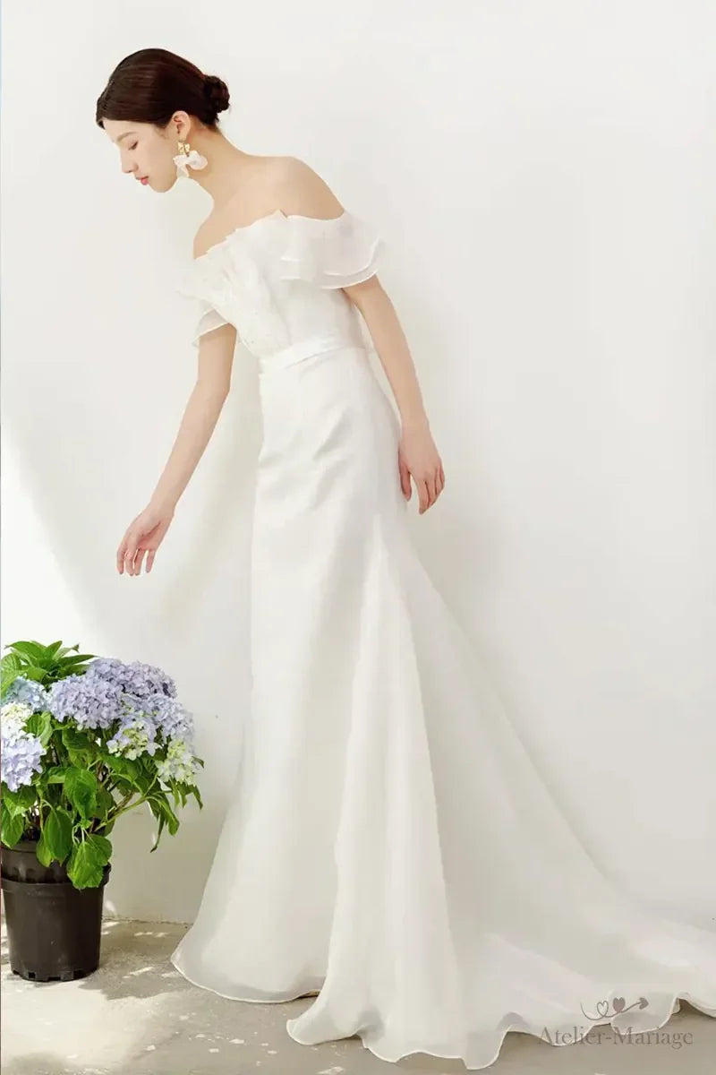 Femme en robe de mariée chic et simple bohème se penchant pour regarder les fleurs

