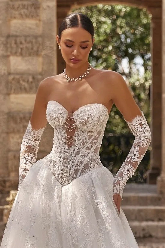 Détail de la délicate finition au poignet des manches amovibles en dentelle simple épaisseur, allongeant visuellement les bras de la mariée.