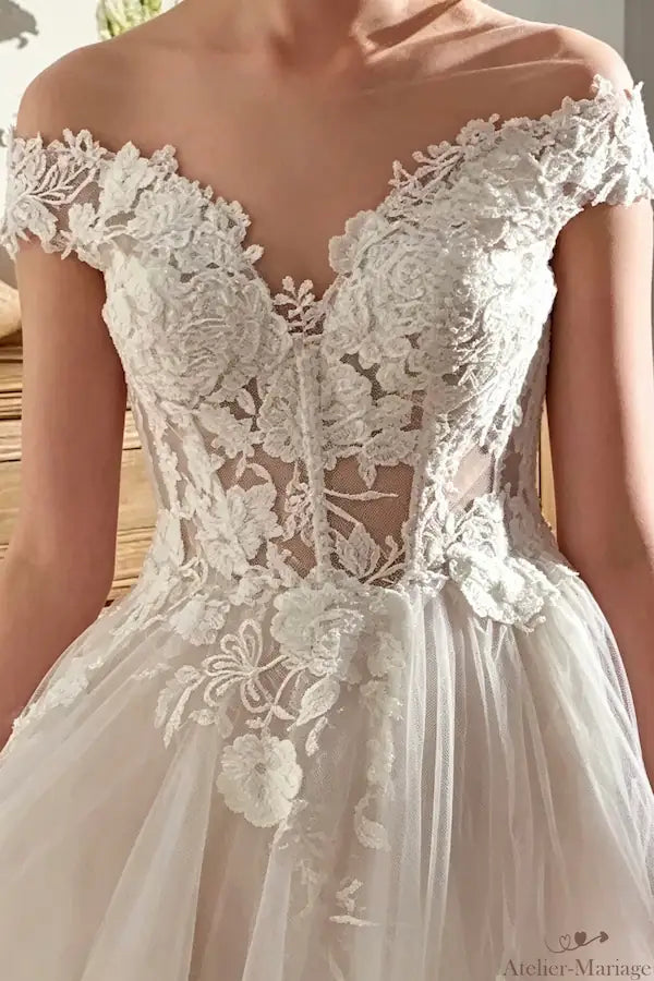 Finition artisanale de la dentelle sur une robe de mariée col bateau bohème.