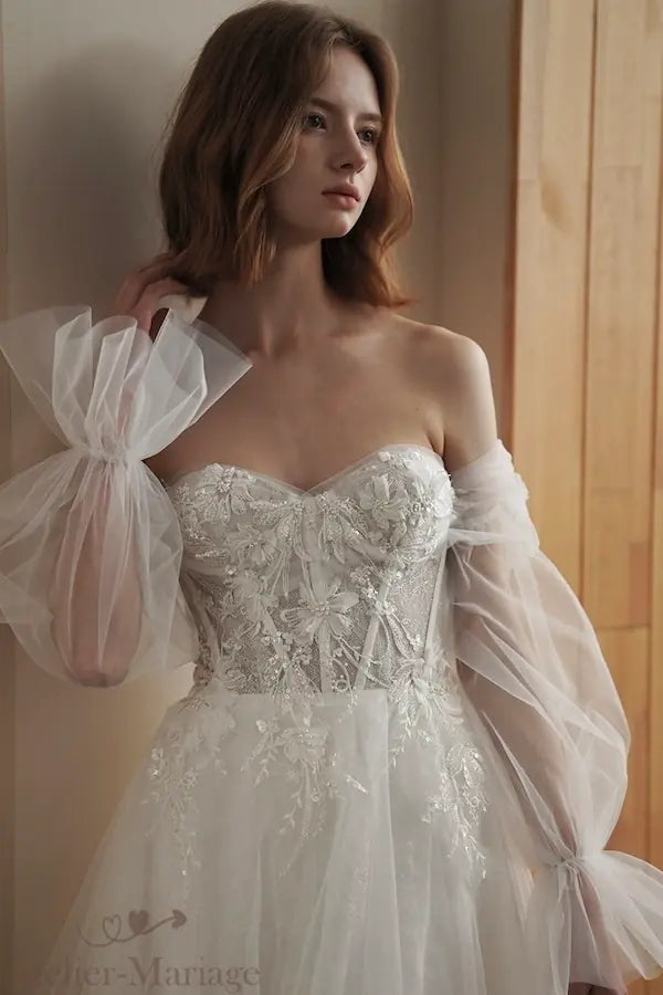Look de mariée bohème avec manches évasées s'intégrant au col bardot.
