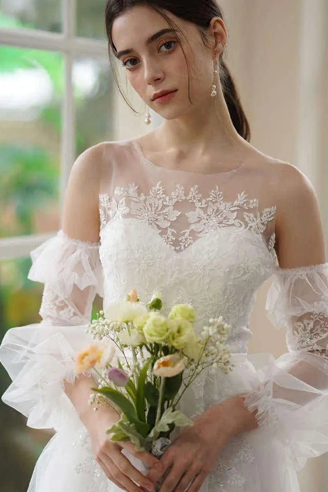 Détail de manche robe de mariée amovible en tulle avec broderie dentelle et sequins brillants, forme bouffante.