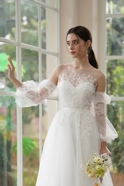 Vue latérale de manches amovibles en tulle transparent forme lanterne, montrant le volume aérien et les motifs de dentelle florale sur le bras.